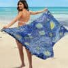 Paréo Artistique Inspiré de Van Gogh tenu par une femme en maillot de bain sur une plage avec la mer en fond